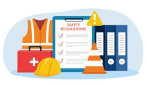 workplace safety conceptual image - safety regulations checklist on a clipboard surrounded by a construction helmet, safety vest, safety cone nad first aid kit